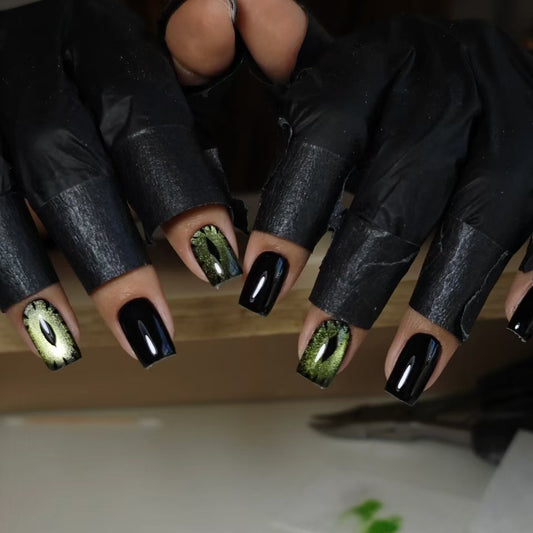 A set of press-on nails featuring black and green streaks with a short square design, displayed on a person's hands.