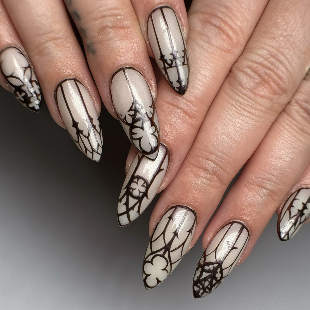 A set of press-on nails featuring a floral design in black and white color scheme, with a gothic style.