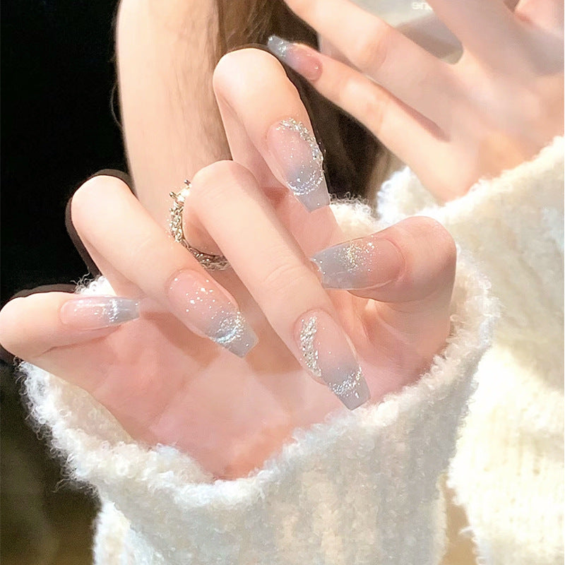 Close-up of hands with glittery nail polish wearing a white textured garment.