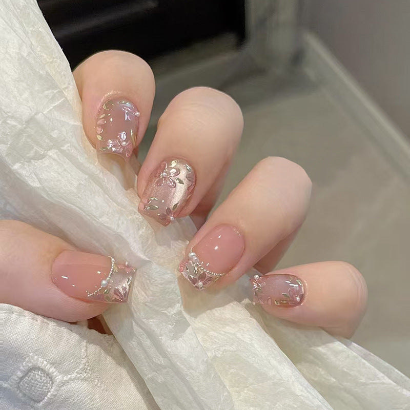 A set of short square nails with pink floral patterns and shimmering detailing.