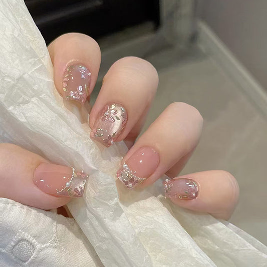 A set of short square nails with pink floral patterns and shimmering detailing.