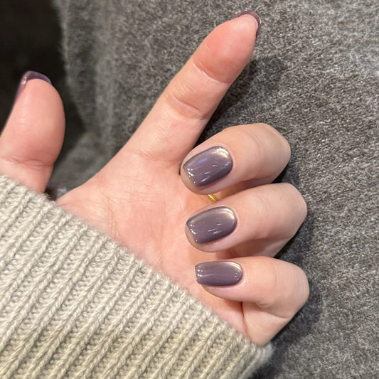 Close-up of a hand with purple nail polish wearing a gray sweater.