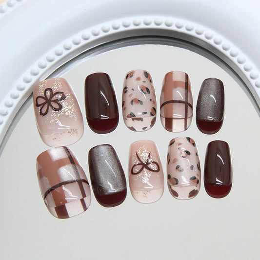 A collection of press-on nails in neutral brown and beige colors with various artistic patterns like animal prints, dots, and stripes displayed on a white surface.