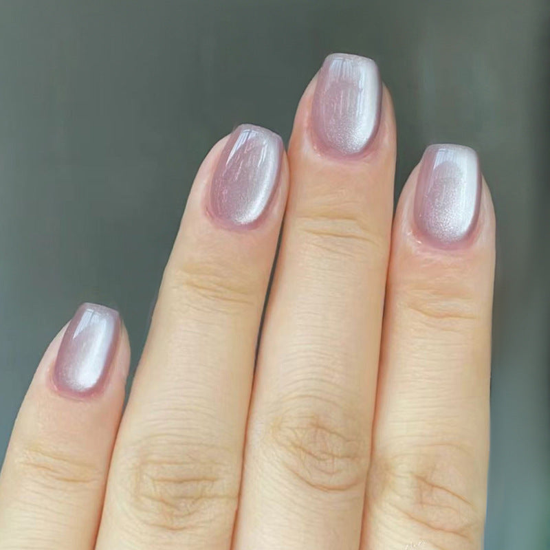 Hand with light pink nail polish on a blurred background
