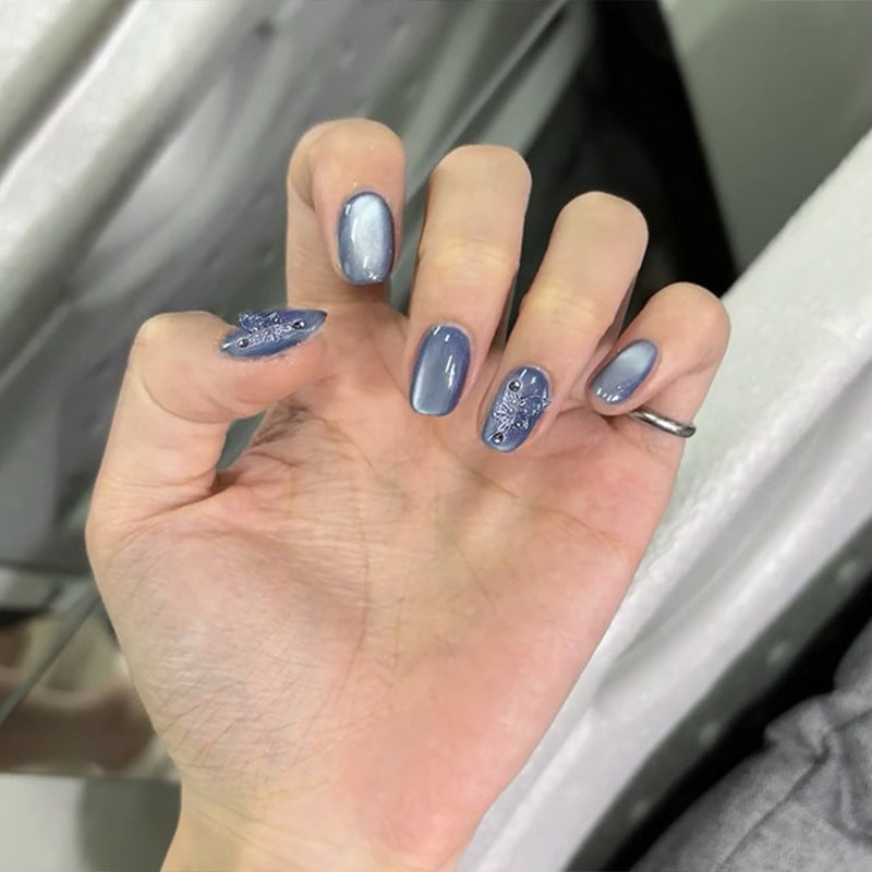 Hand with blue nail polish holding a phone, blurred background