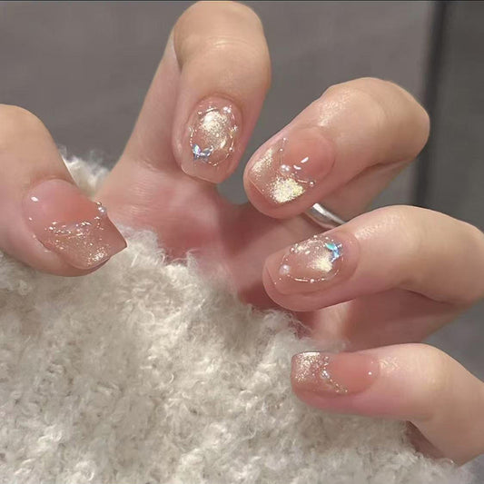 Close-up of a hand with glittery nail polish on a textured surface