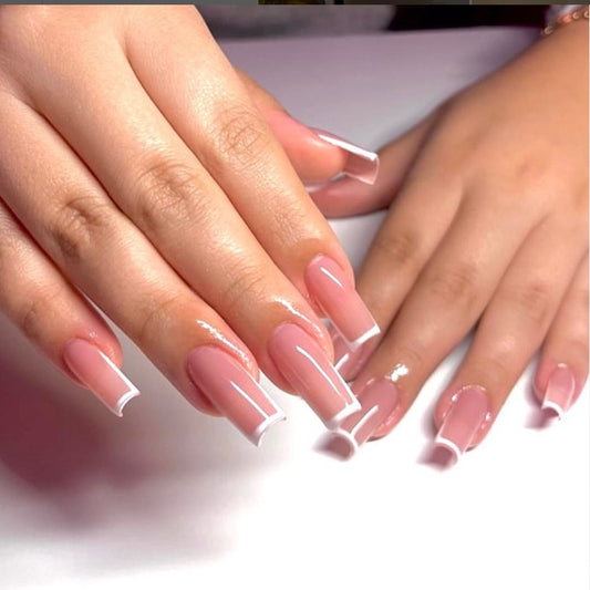 A set of press-on nails with elegant white tips and a high gloss finish, displayed on a person's hands.