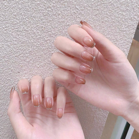 A pair of hands with medium squoval press-on nails with accent glitter, displayed against a neutral background.