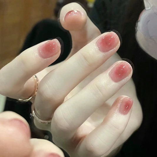 Close-up of a hand with pink nail polish on a blurred background
