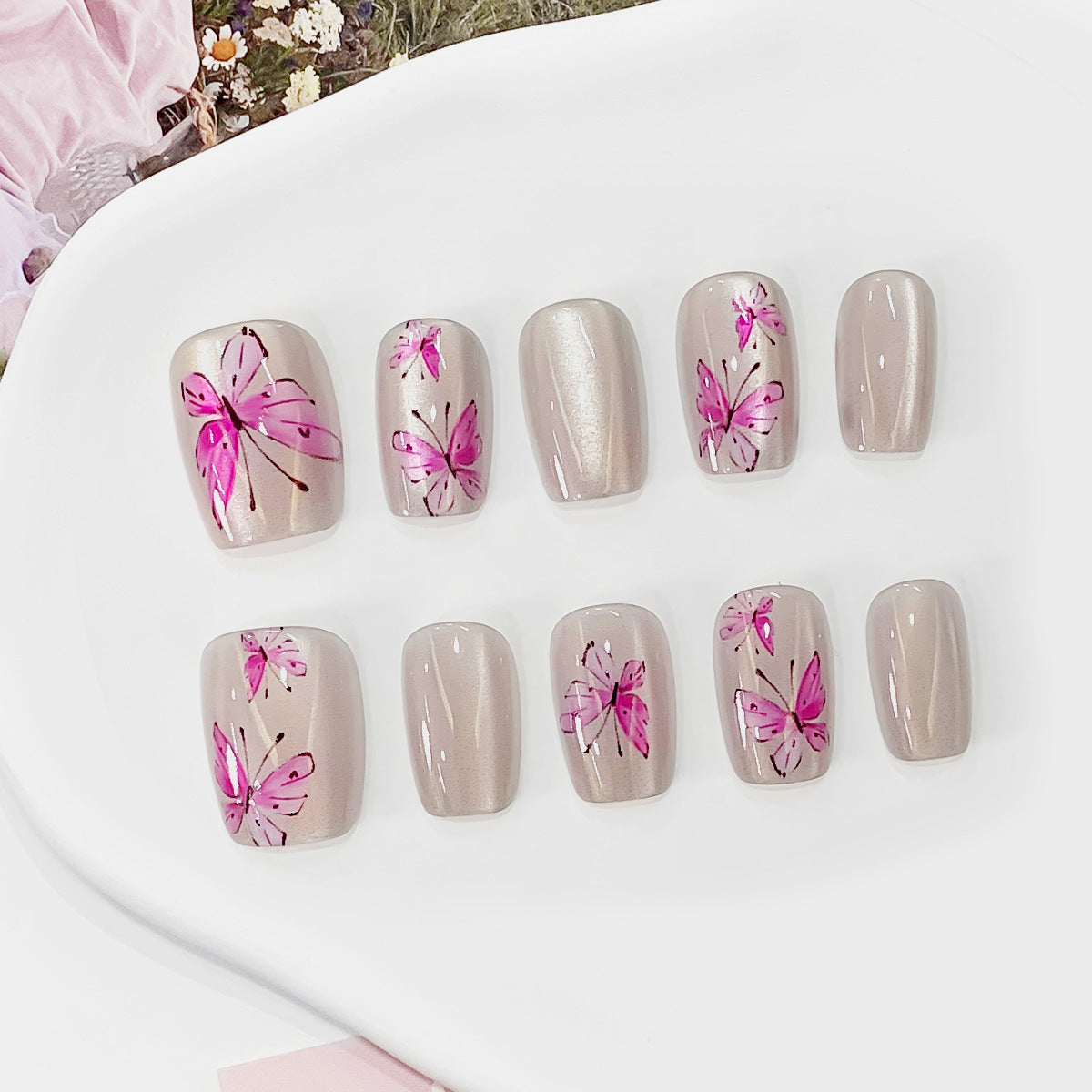 Nail art with pink floral designs on a white surface