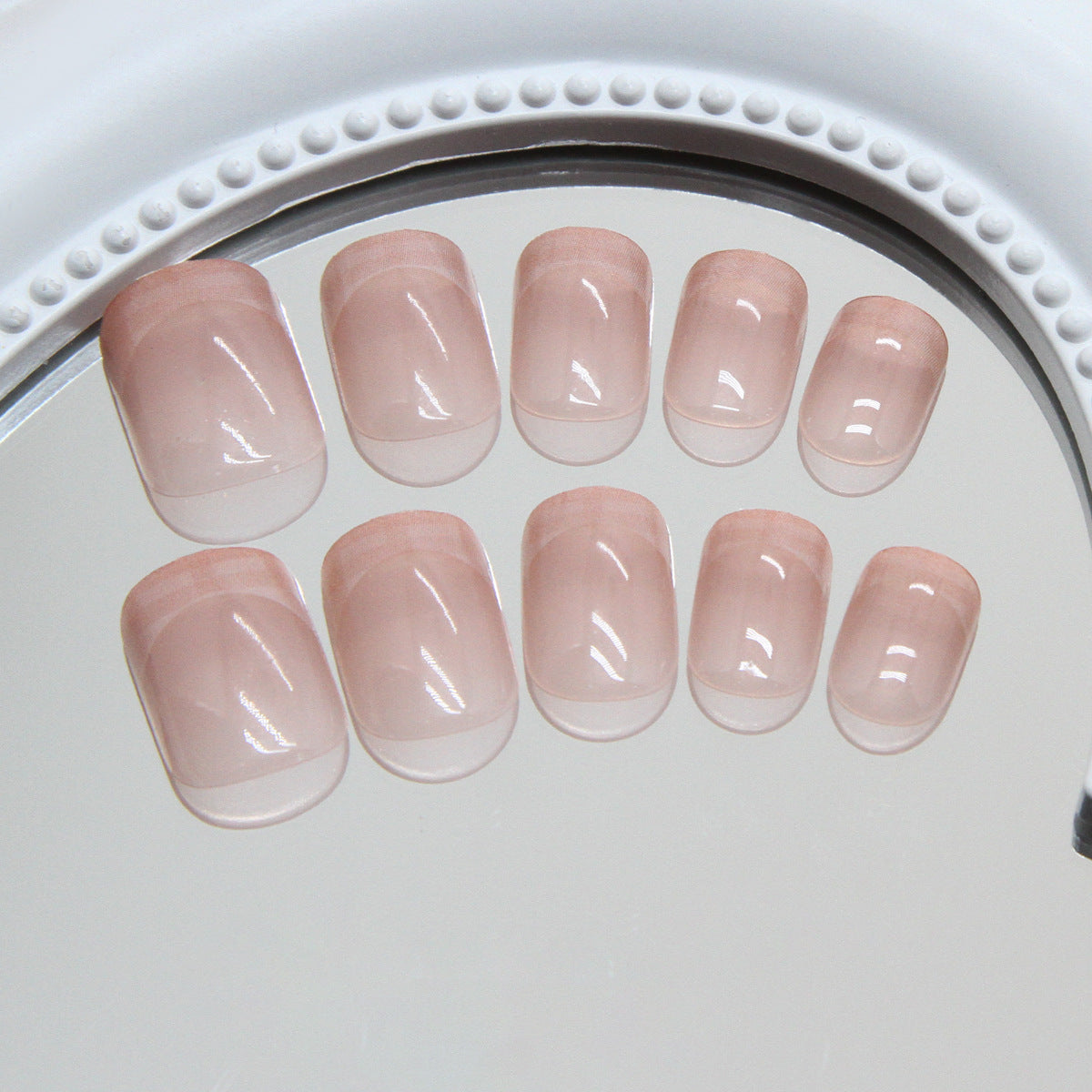 A set of extra short squoval pink glossy press-on nails displayed on a white surface.