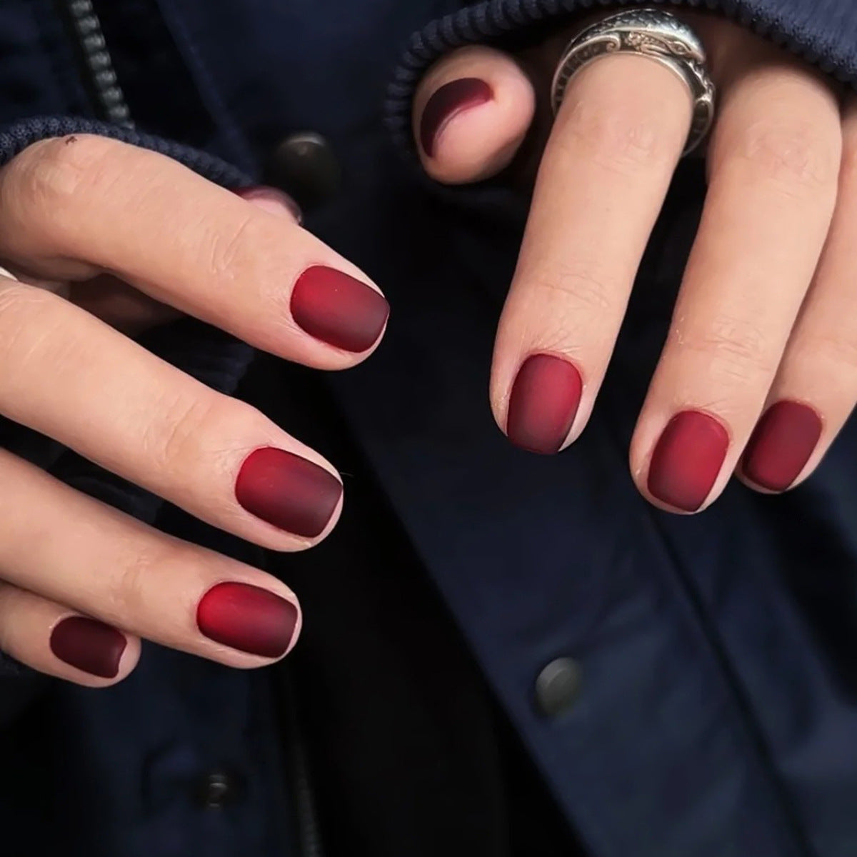 Close-up of hands with red nail polish against a dark background