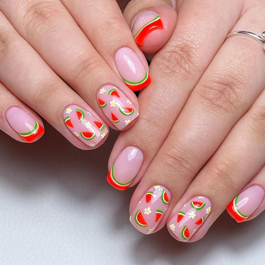 A set of press-on nails featuring a watermelon design with green, red, and white stripes and daisy accents, displayed on a hand.