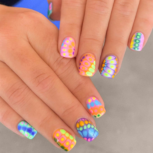 Close-up of hands with colorful nail art on a neutral background