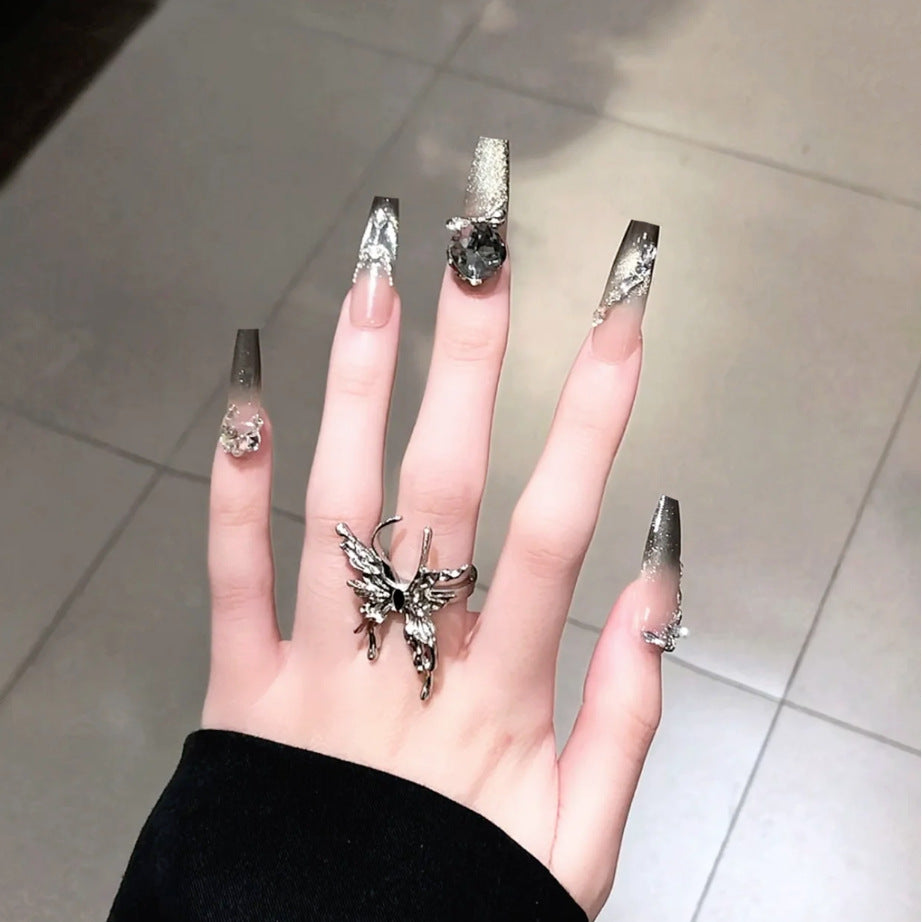 Hand with decorative nails and rings on a tiled floor background