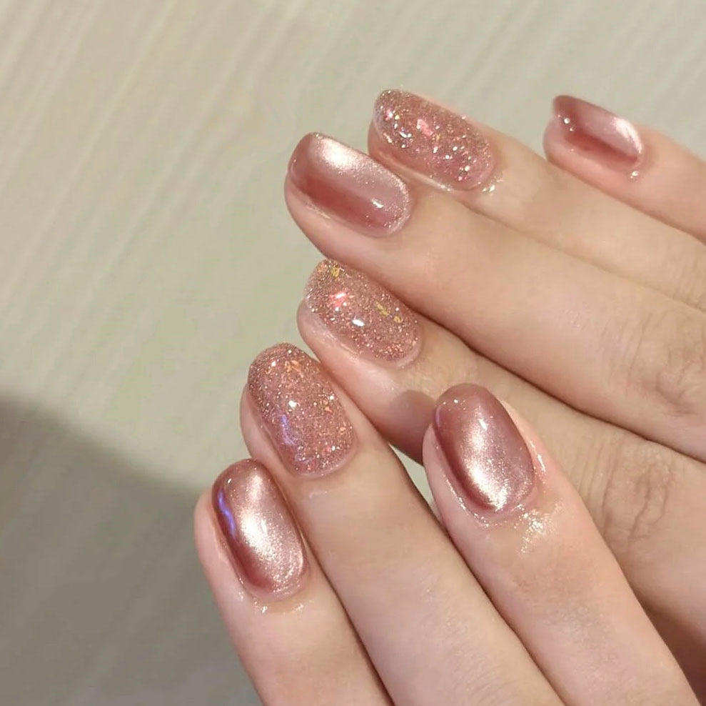 Hand with pink glittery nail polish on a neutral background