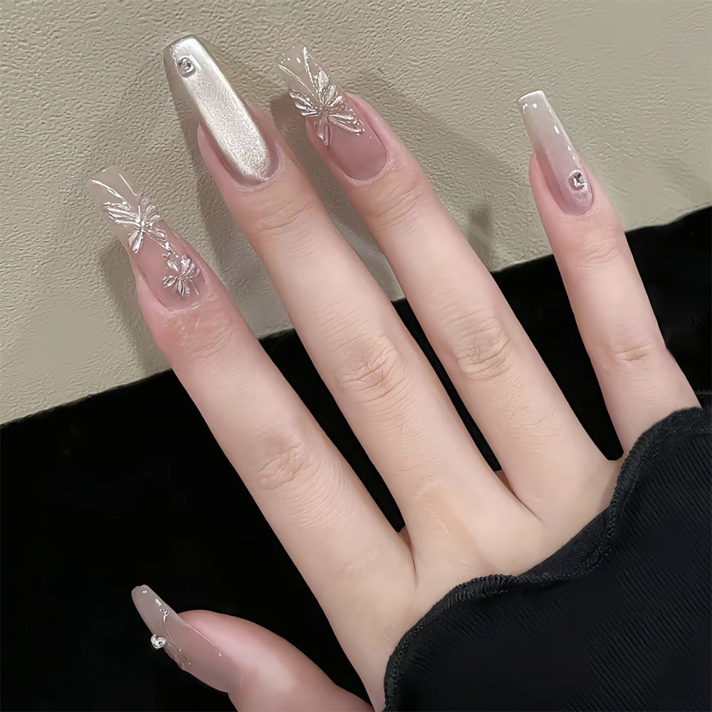 A set of long, clear, and silver press-on nails with a floral design, displayed on a hand against a dark background.