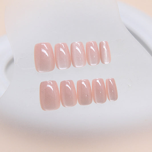A set of short square-shaped pink glossy nails with an iridescent finish displayed on a white surface.