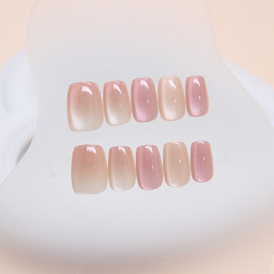 A set of press-on nails with a glossy finish, featuring a soft pink ombre color.