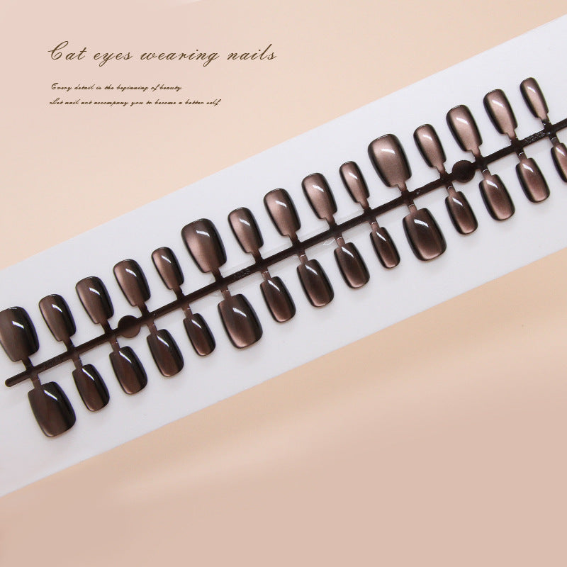 A set of false nails laid out in a row, featuring a brown cat eye design.