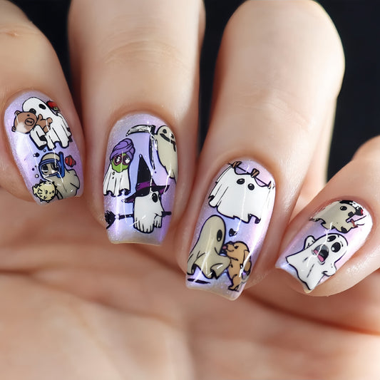 A set of press-on nails featuring colorful Halloween character designs, including ghosts and pumpkins, on a purple background.