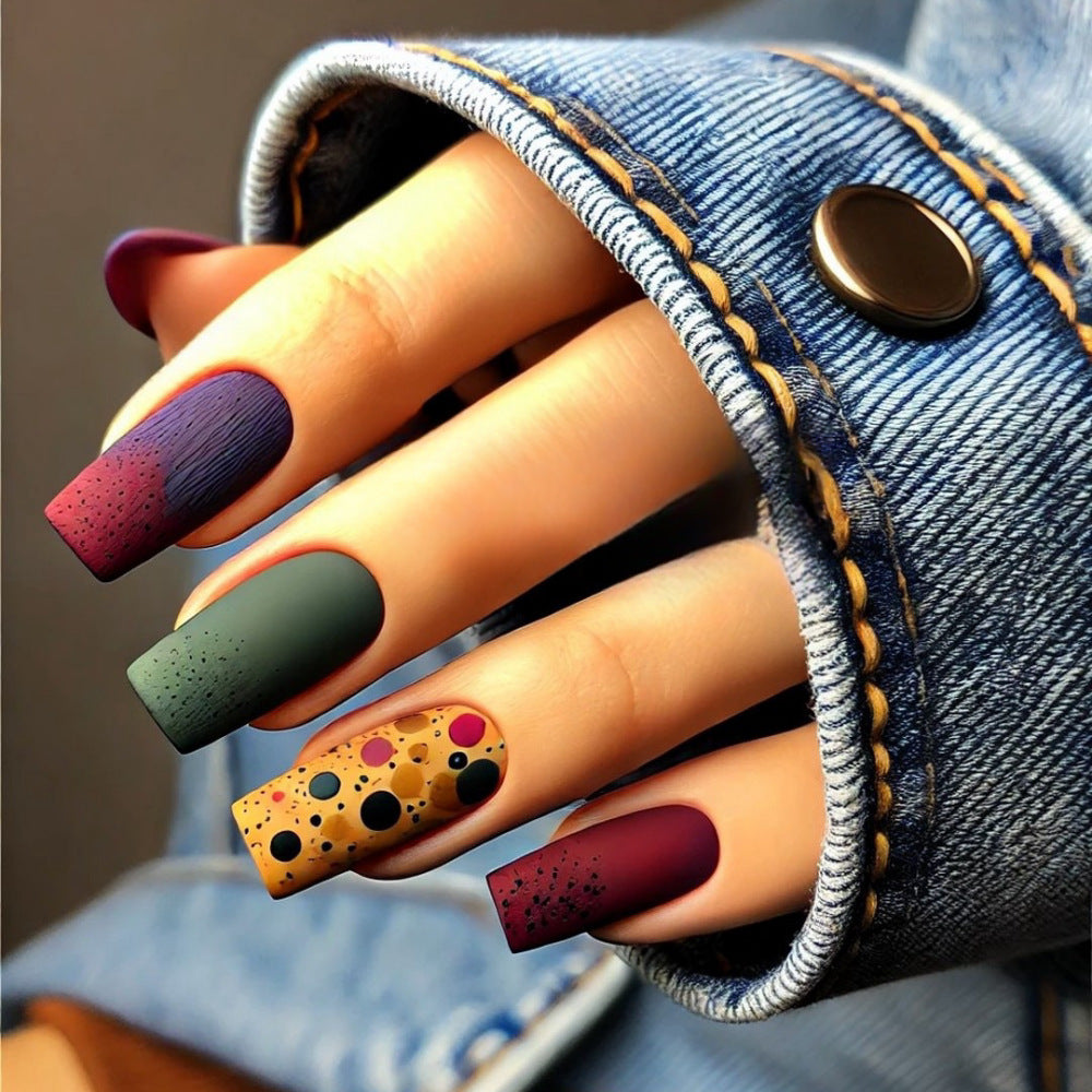 Close-up of a hand with colorful nail art wearing a denim jacket.