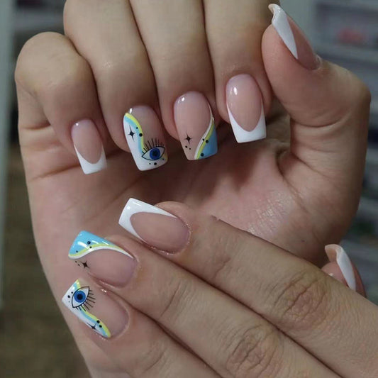 Close-up of hands with decorative nail art featuring eyes and abstract designs.