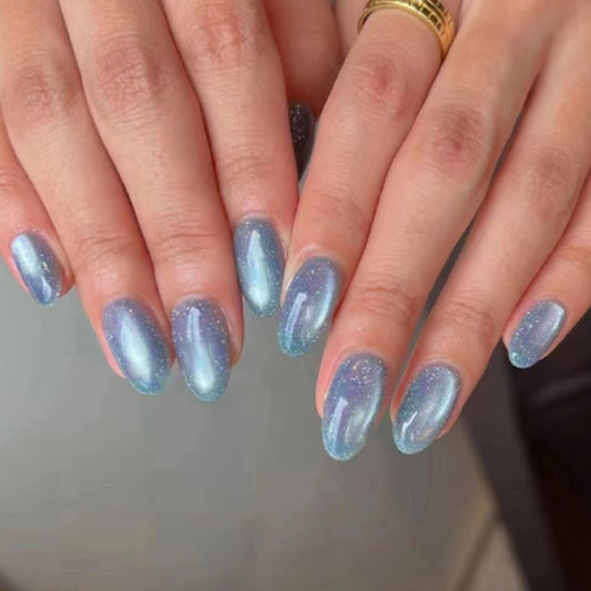 A set of press-on nails with a gradient color transition from blue to a lighter shade, featuring a sparkling glitter finish.