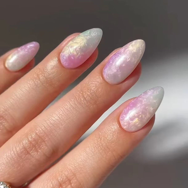 A set of long almond-shaped press-on nails with a pearl pink iridescent finish and shimmering ocean glow.