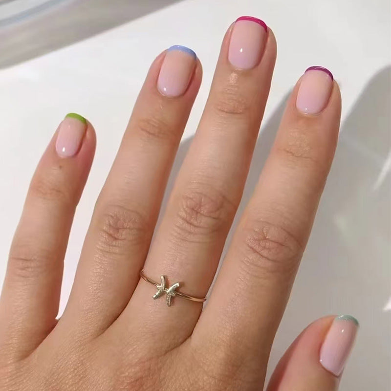 A set of press-on nails featuring a variety of colors including pink, blue, green, and purple, applied in a glossy finish.