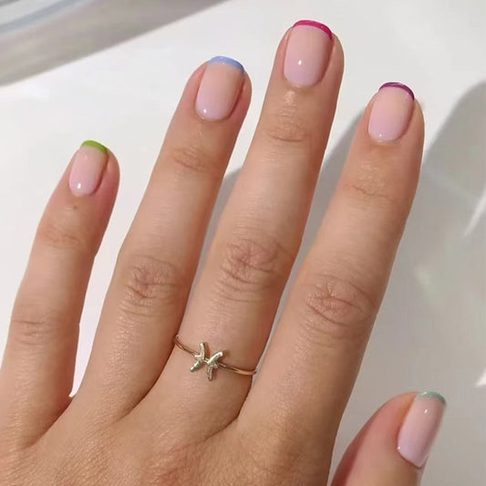 A set of press-on nails featuring a variety of colors including pink, blue, green, and purple, applied in a glossy finish.