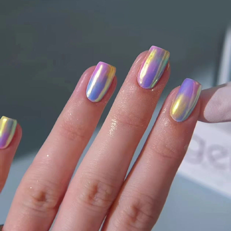 A set of press-on nails with a rainbow aura glossy finish, displayed on a person's hand.