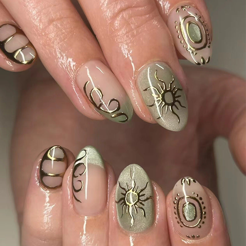 A set of press-on nails featuring almond green and beige colors with gold sun and abstract designs.