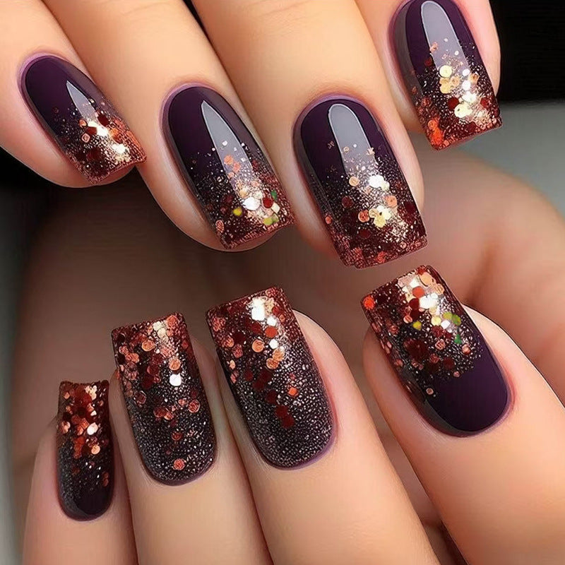 A set of press-on nails showcasing a gradient design with deep purple at the base, transitioning into a sparkling glitter finish.