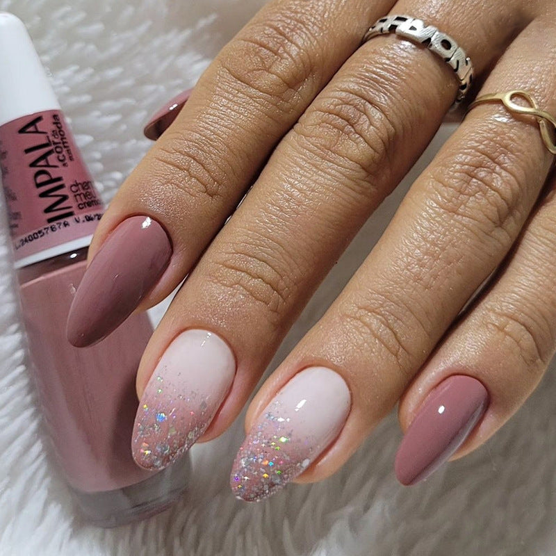 Hand with pink and glittery nails holding a bottle of Impala nail polish.
