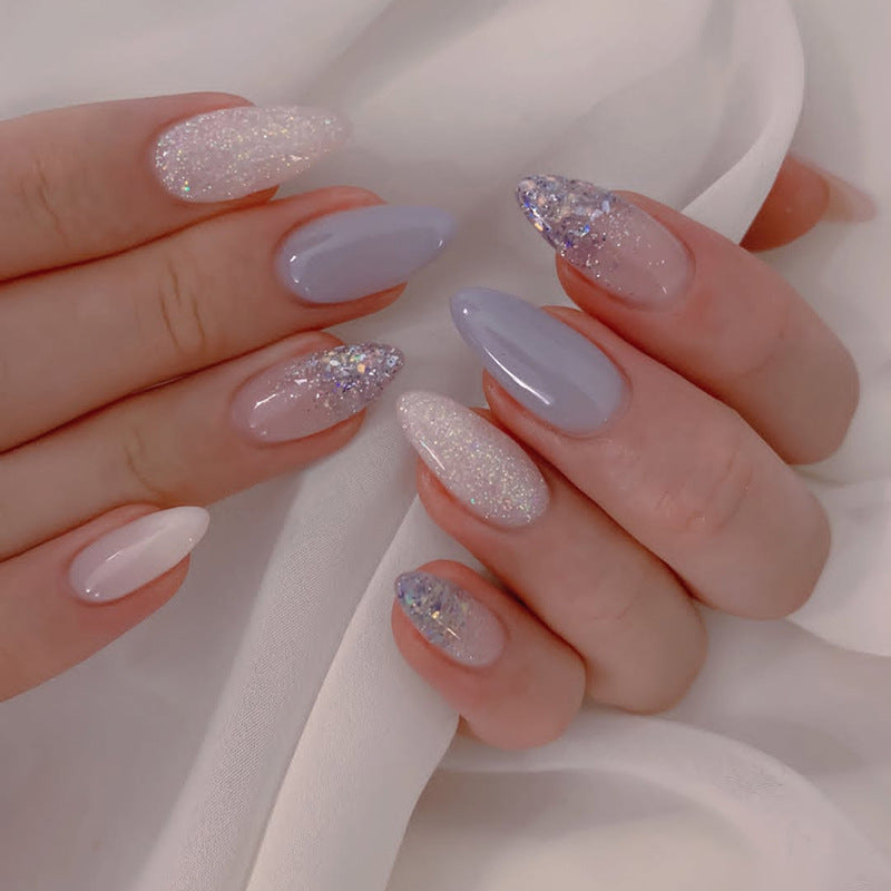 Close-up of a hand with glittery and pastel nail designs on a white background