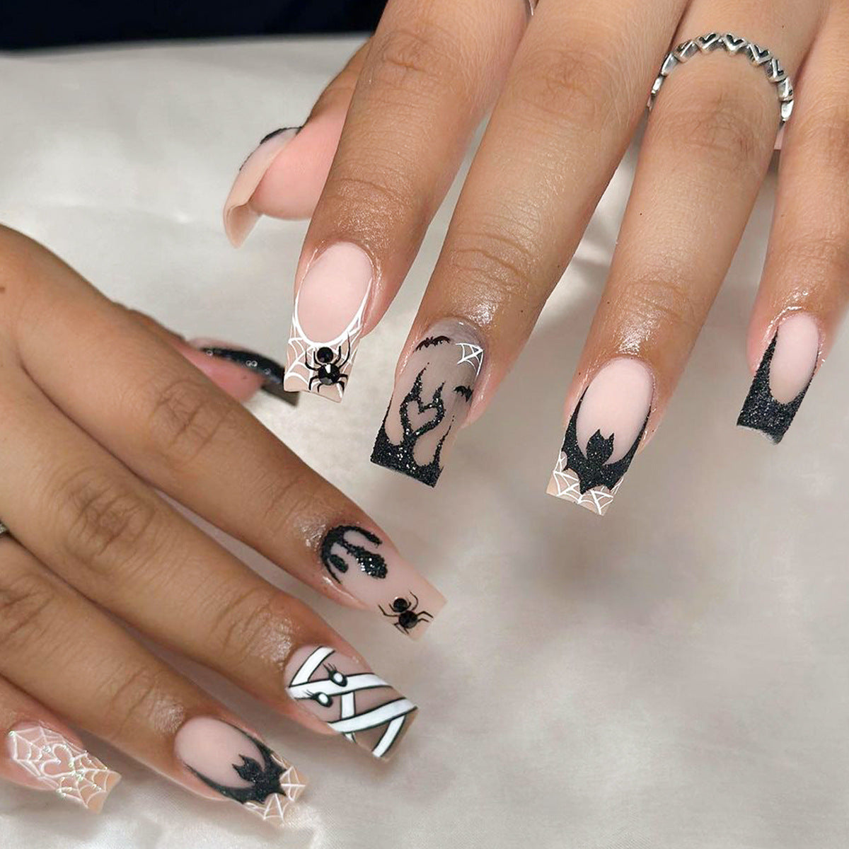 Nails with Halloween-themed designs featuring spiders and webs on a neutral background