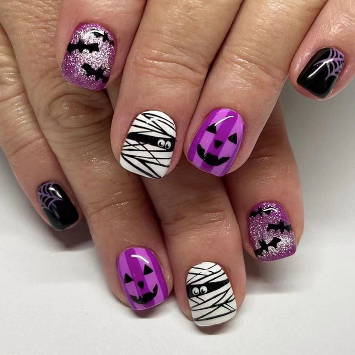 A set of press-on nails featuring a Halloween theme with designs including a mummy and pumpkin.