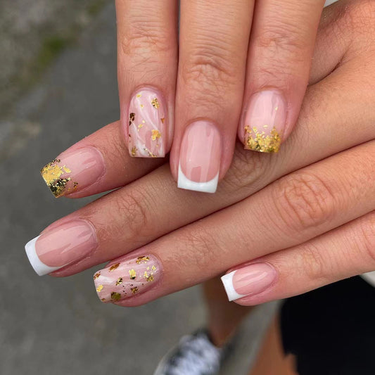 A set of press-on nails featuring a natural pink base with gold flakes and a French tip design.