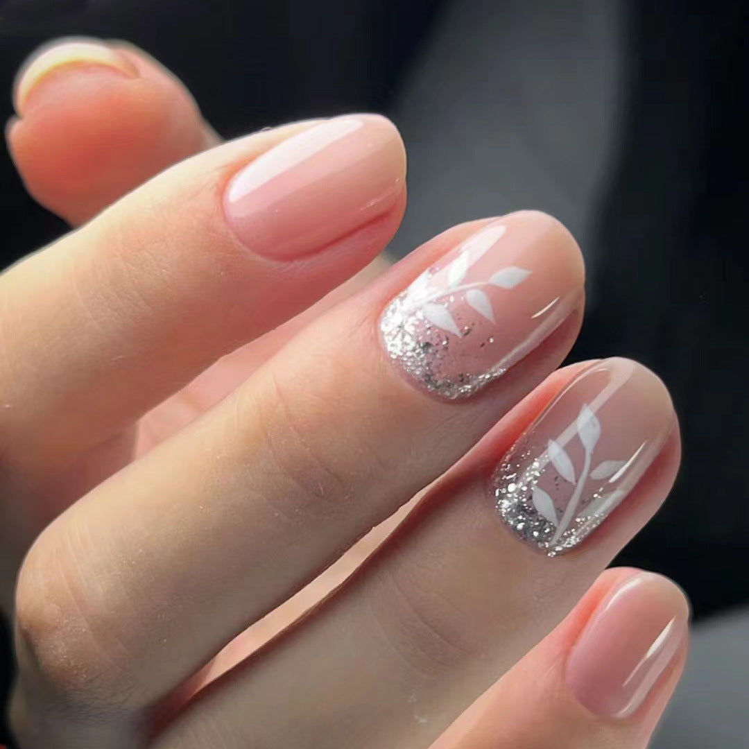 A set of press-on nails with silver glitter accents, presented in a subtle beige color.