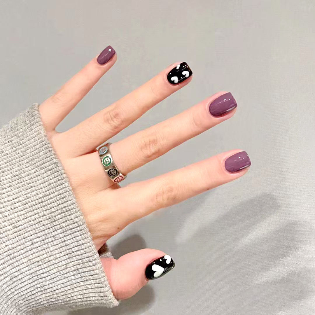 Hand with purple and black nail design on a gray background