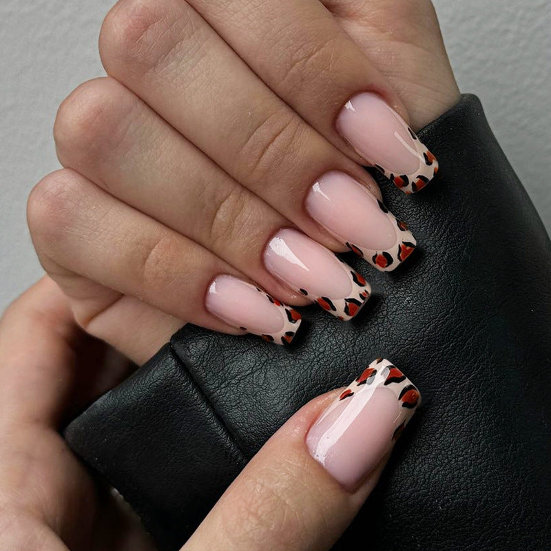 Close-up of hands with pink nails and black and red pattern holding a black leather bag.