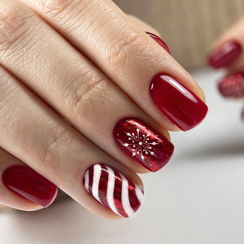 Close-up of a hand with red nail polish featuring decorative patterns on a neutral background