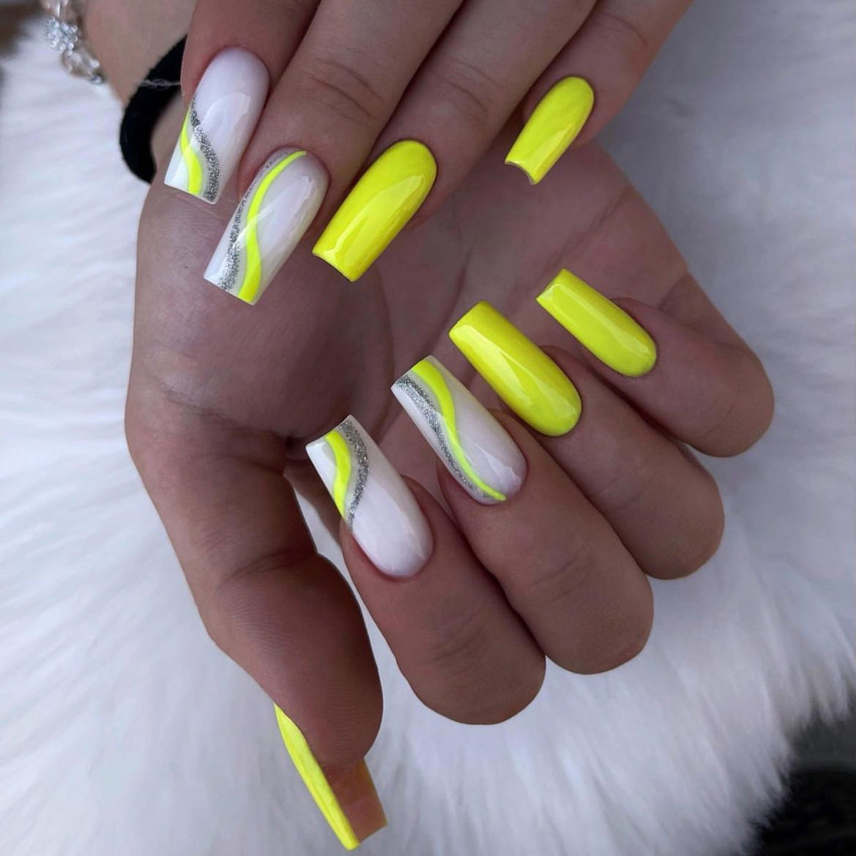 Hand with neon yellow and white nail design on a white background