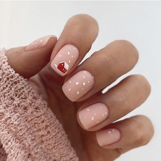 Hand with pink nail polish and a red heart design on a white background