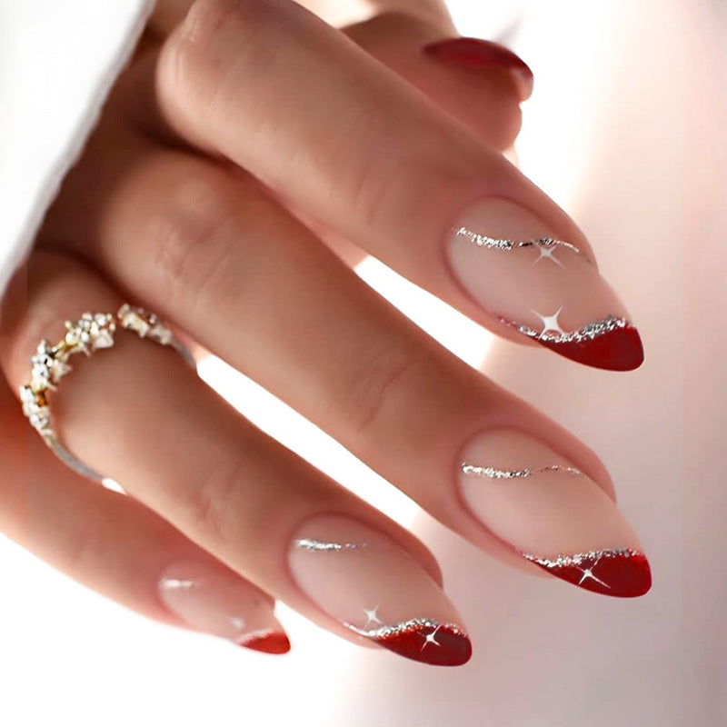 A close-up of a hand showcasing press-on nails with a transparent base and red glitter tips.