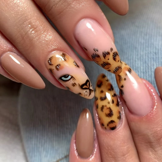 A set of press-on nails featuring a beige almond shape with leopard print design and animal face details.