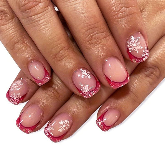 Nails with pink and red design featuring snowflakes on a white background