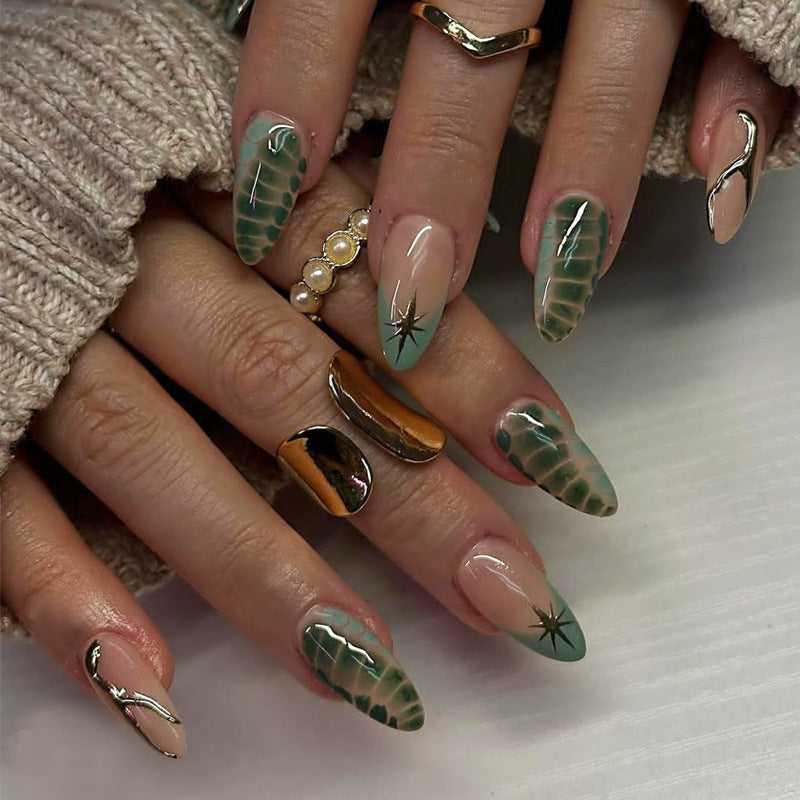 A set of press-on nails featuring an ombre design with green, almond-shaped nails and star accents, displayed on a person's hand.