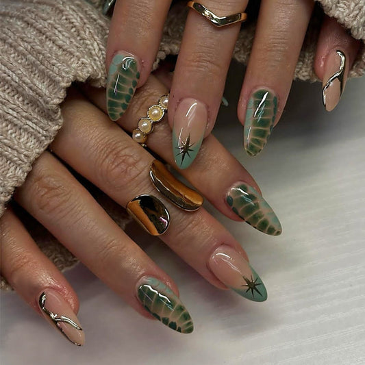 A set of press-on nails featuring an ombre design with green, almond-shaped nails and star accents, displayed on a person's hand.